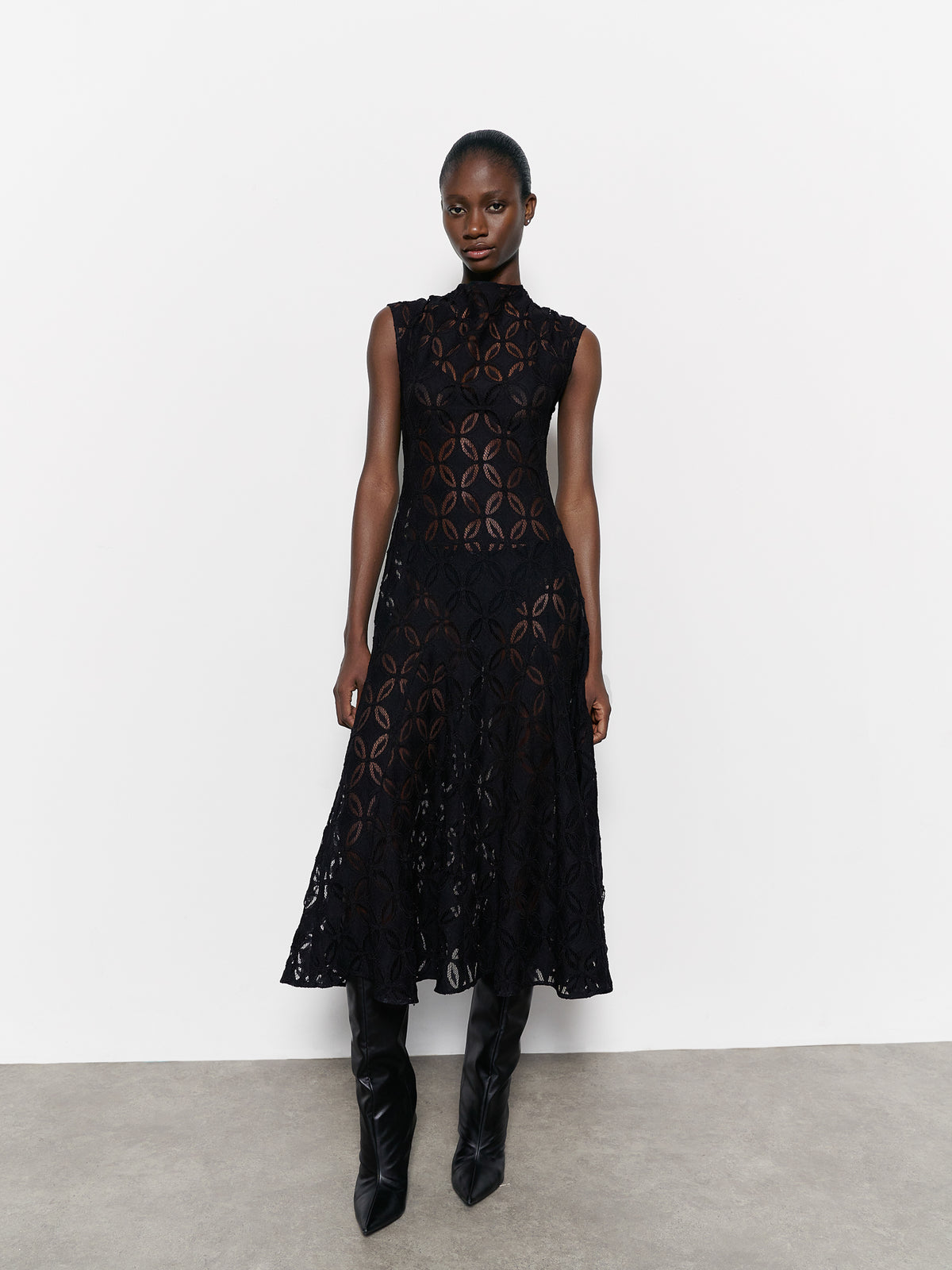 Model wearing a black lace dress against a white background