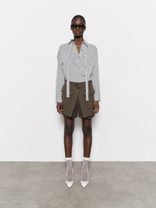 Model wearing a white and black stripe shirt , dark green shorts, and white shoes on a plain background